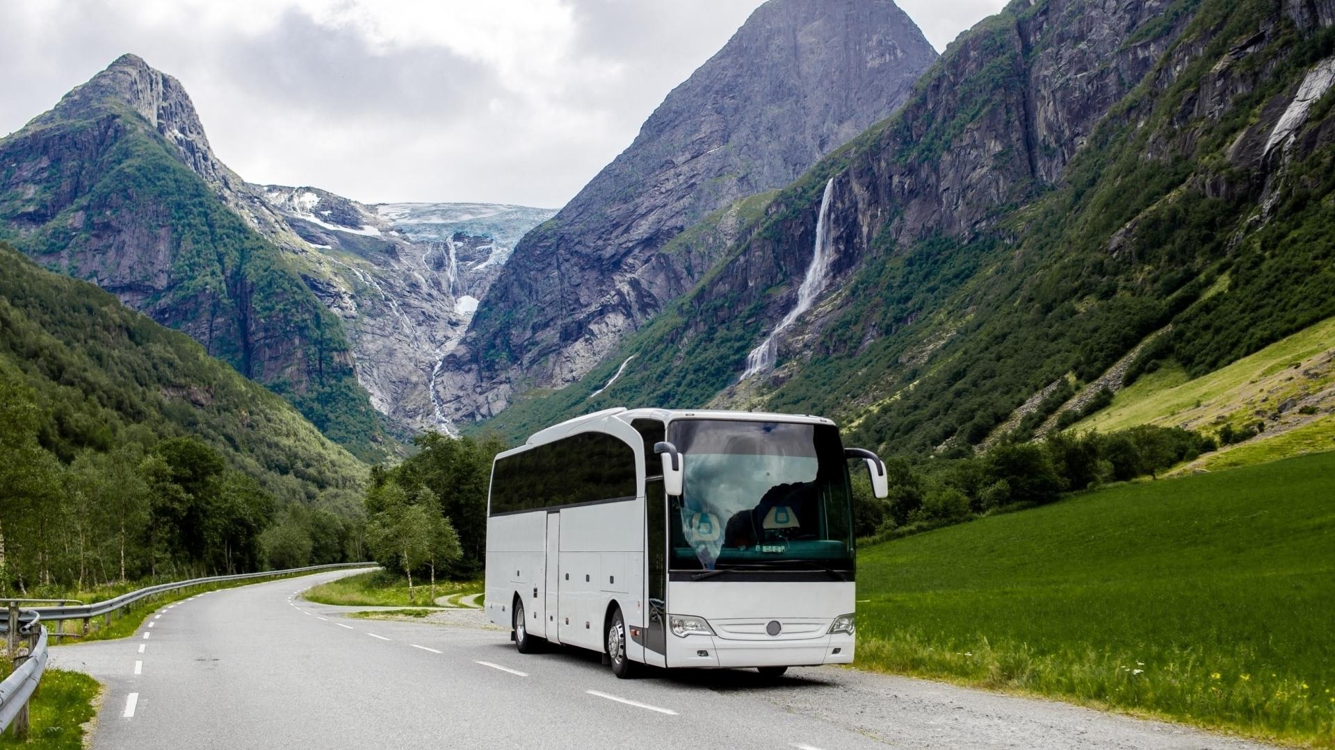 En hvit buss blandt fjell og vakker natur. Foto