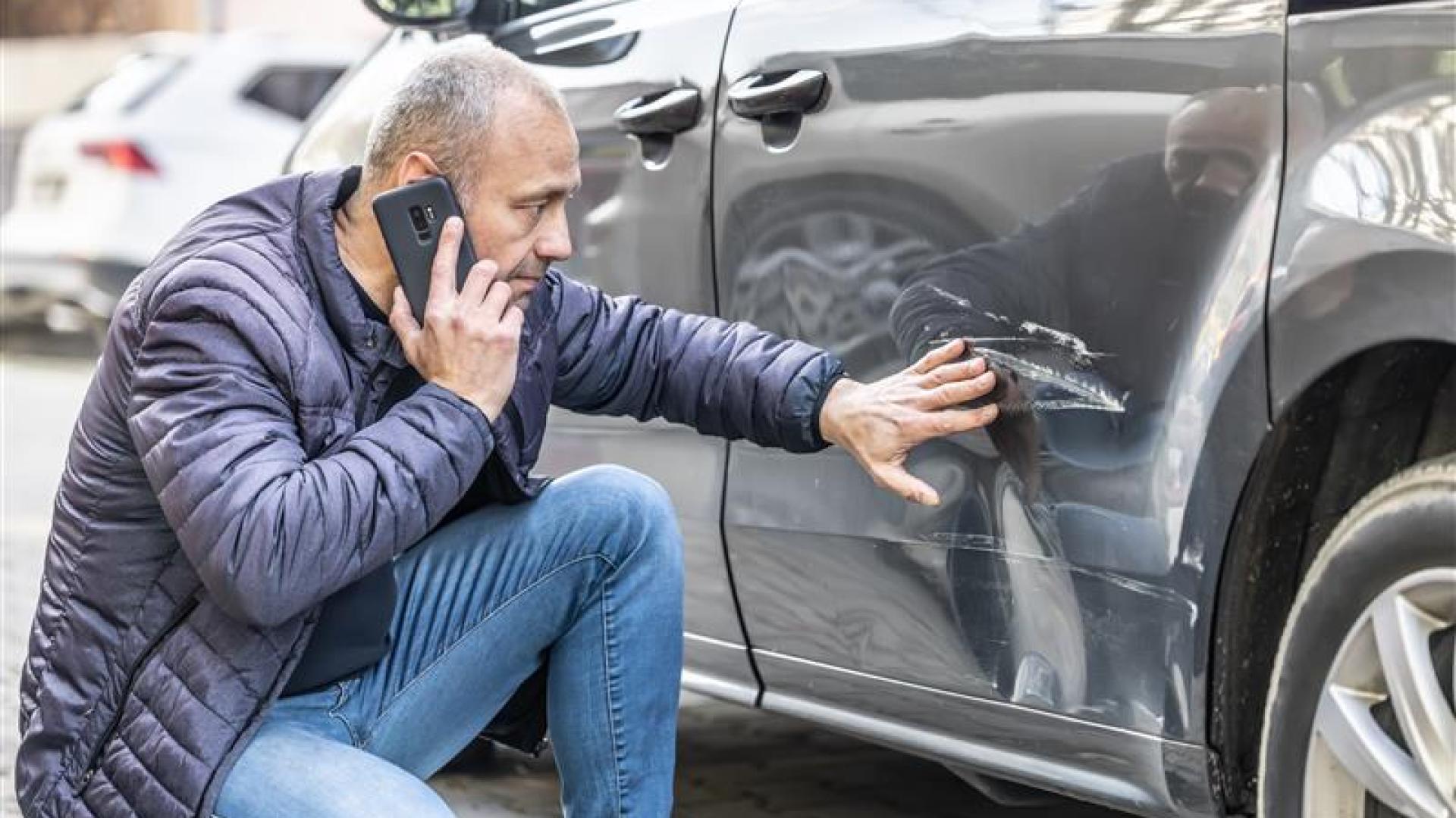 Mann som ser på skade på bilen