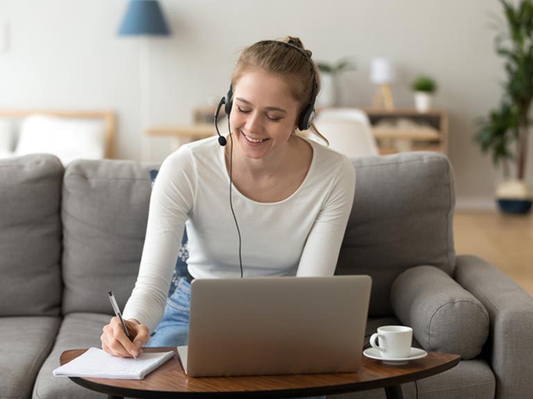 Jente bruker laptop fra sofaen