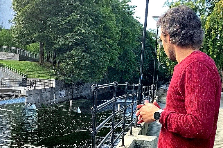 Mann står og ser på Akerselva hvor han nesten druknet