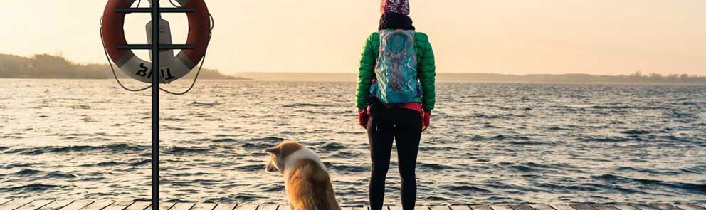 Kvinne og hund ser ut mot sjøen