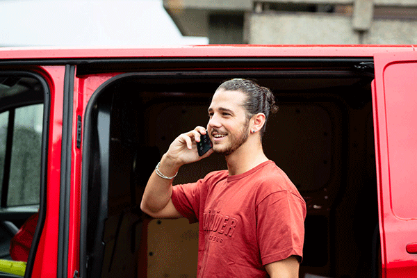 Mannlig håndverker foran firmabil snakker i telefonen