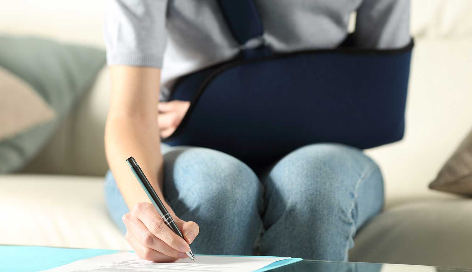 Kvinne med skadet arm skriver på dokumenter