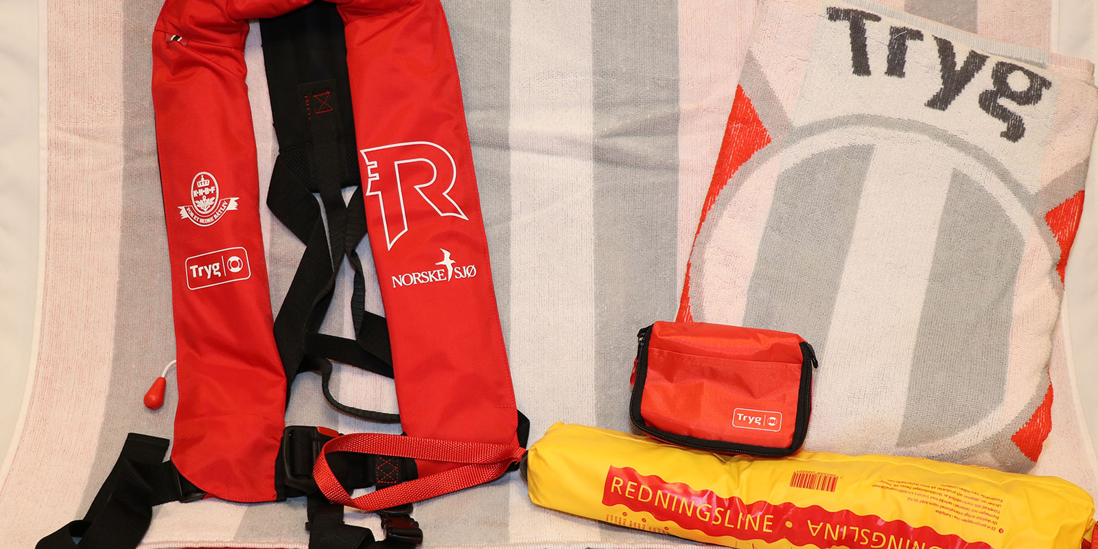 Redningsvest, redningsline, førstehjelpspute og to strandhåndklær