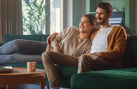 Mann og kvinne sitter sammen på sofa i stue