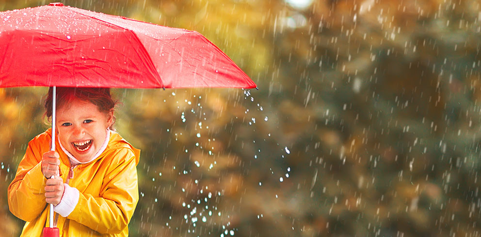 Jente smiler under en rød paraply