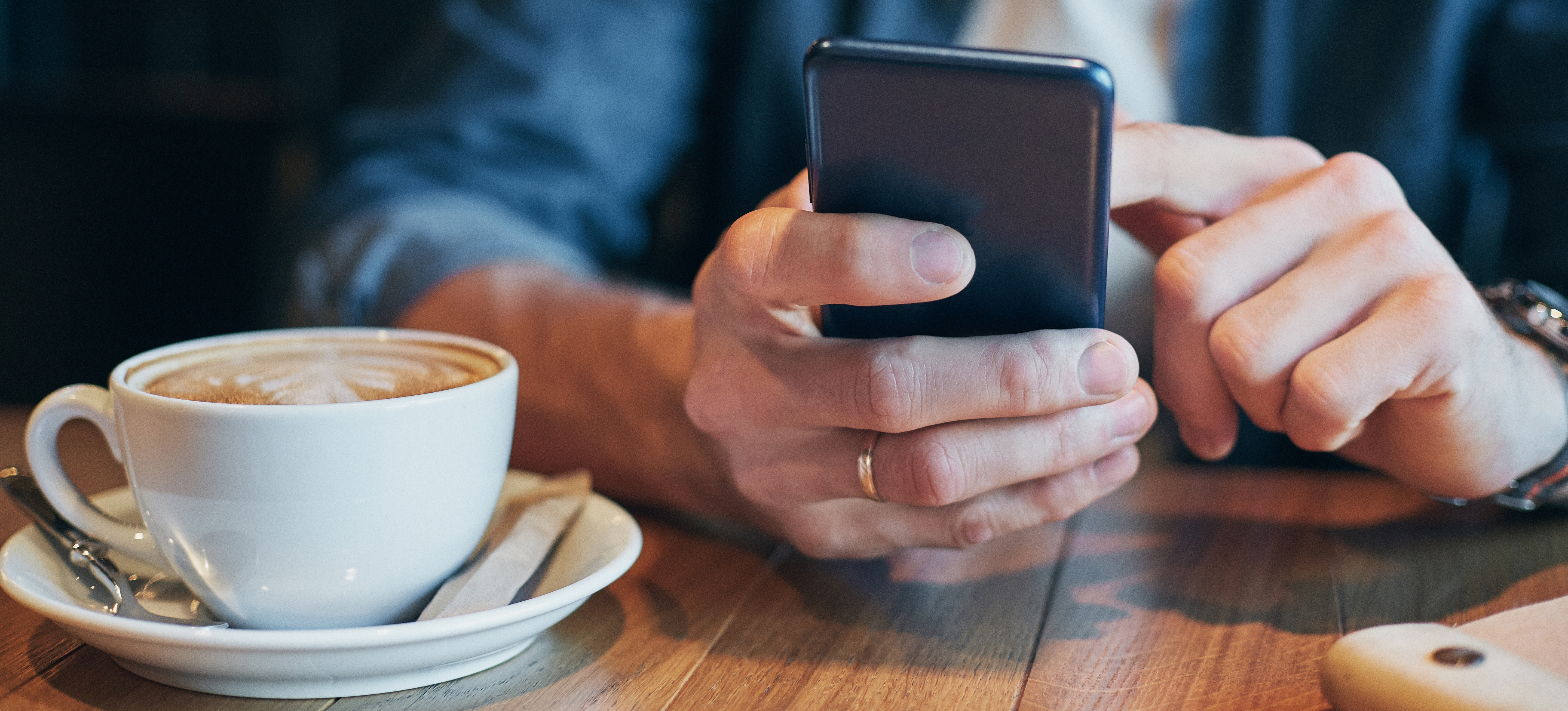 Nærbilde av mobiltelefon og kaffekopp 