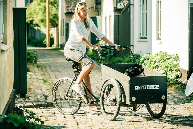 Kvinne sykler i boligområde i solen