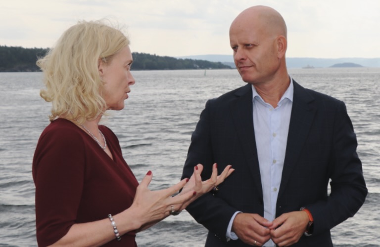 To personer snakker sammen foran sjø.