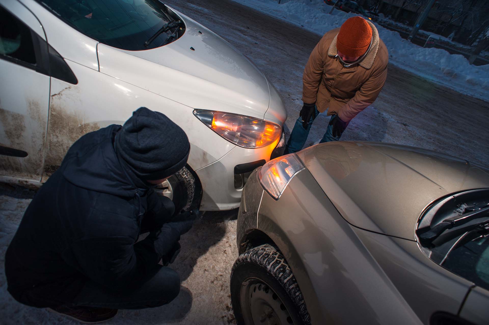 To biler har krasjet front mot front og to personer ser på skadene