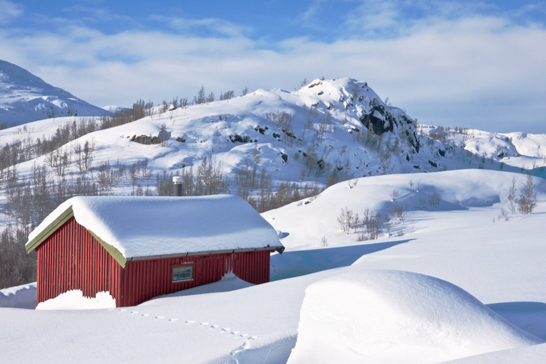 Rød hytte i snødekt vinterlandskap