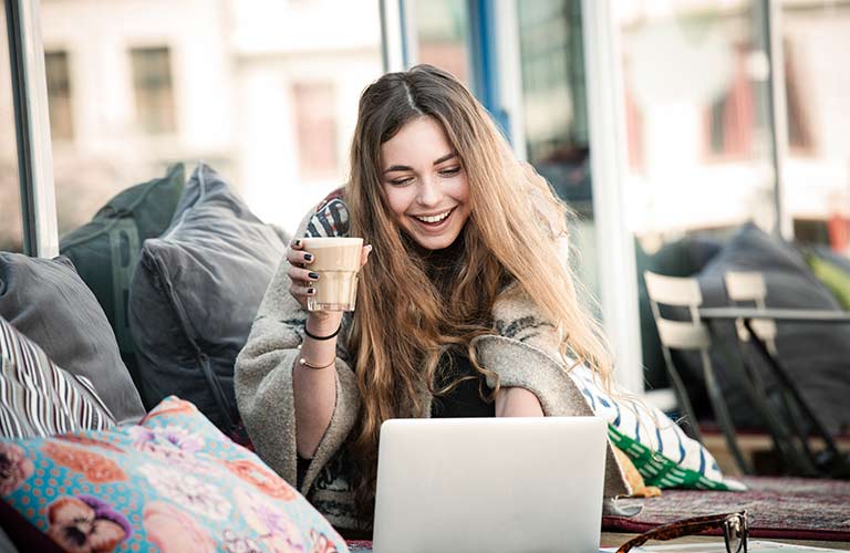 Kvinnelig student ser på laptop på cafe