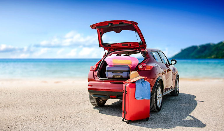 Leiebil med bagasje parkert på strand