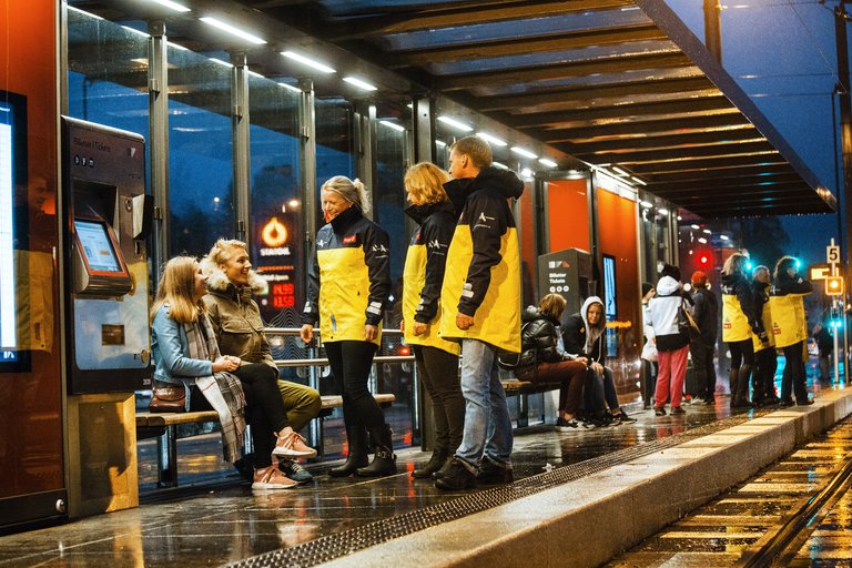 Natteravner står og snakker med ungdom på et busstopp