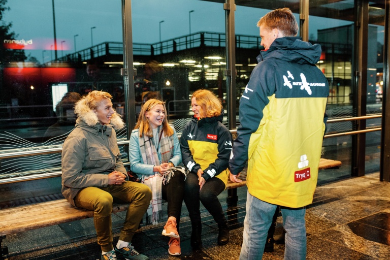 Ungdommer på et busstopp med en voksen Natteravn