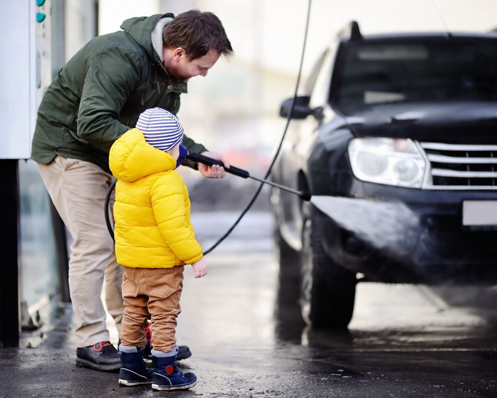 Mann og liten sønn vasker en svart bil.