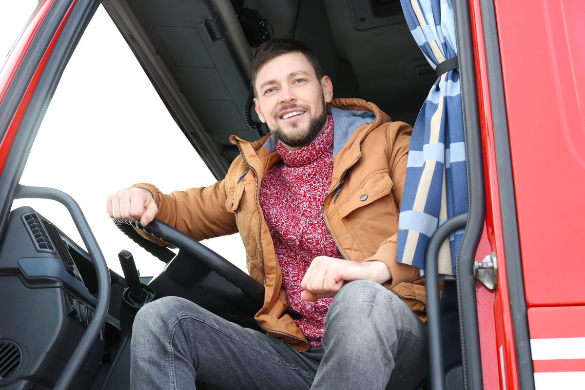 Mann sitter i lastebil med vinterjakke på