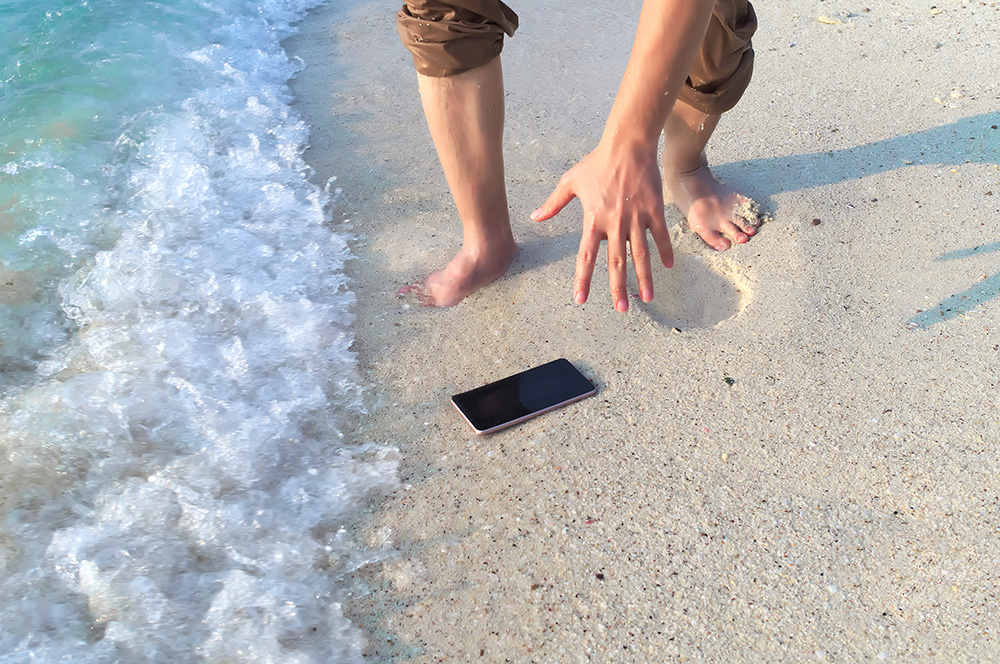 En mobil som ligger på stranden og har blitt tatt av en bølge
