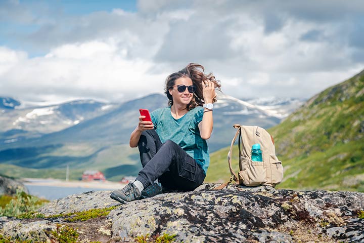 Helårs reiseforsikring - ung kvinne med vind i håret som tar en rastepause i høyfjellet