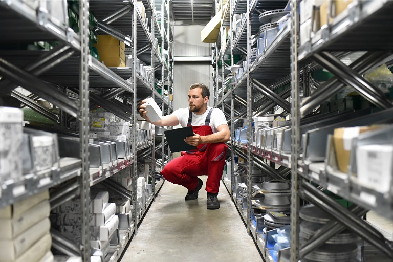 En mekaniker står på et lager og leter etter bildeler