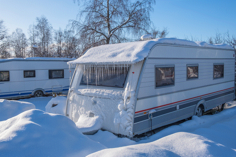 Campingvogn i snølandskap med istapper langs taket