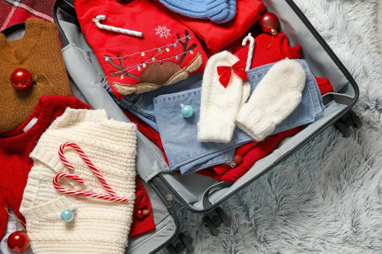 En åpen koffert med julegaver og pent juletøy som skal pakkes