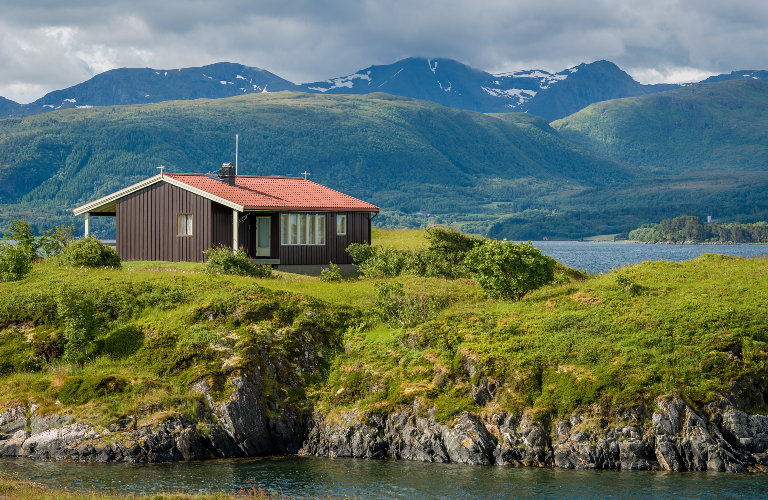 Hytte i fjordlandskap med fjell rundt