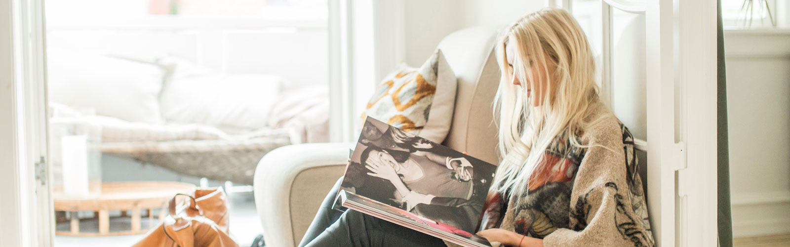 Jente sitter på gulvet og leser en mote bok