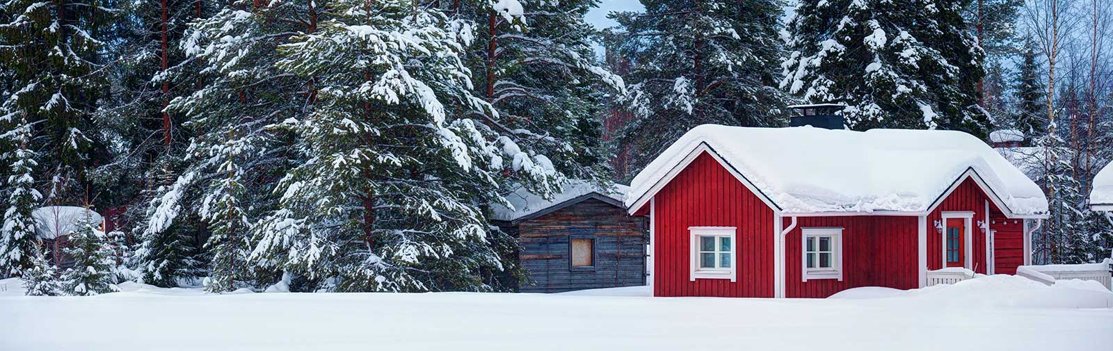 Rød hytte i vinterkledd landskap