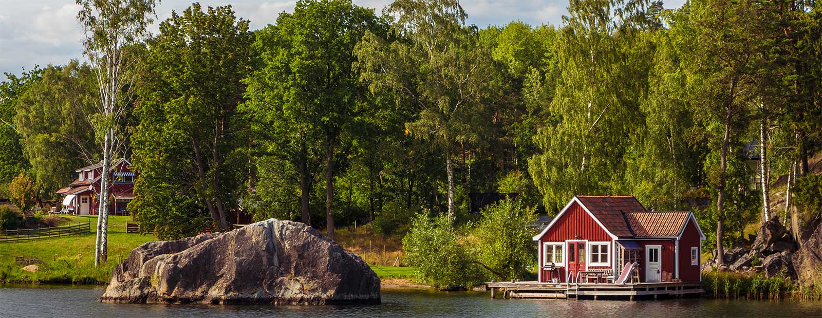 Rød sjøhytte i naturlandskap